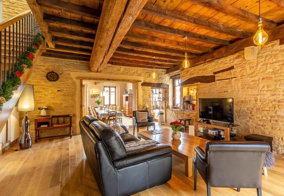 a living room with leather furniture and a wooden ceiling at Très belle demeure Roche de Solutré - 15 personnes in Solutré-Pouilly