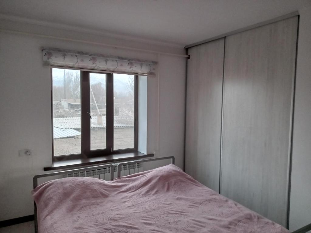 um quarto com uma cama e uma janela em Mairambek em Kochkorka
