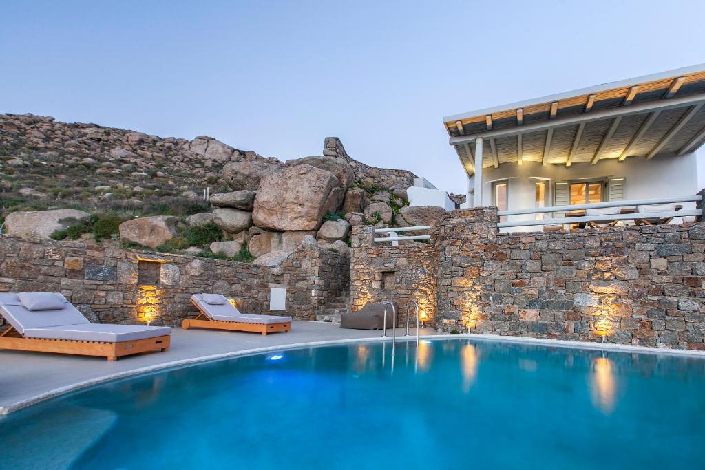 dom z basenem obok kamiennej ściany w obiekcie Breathtaking 6 Bed in Platis Gialos w mieście Platis Gialos Mykonos