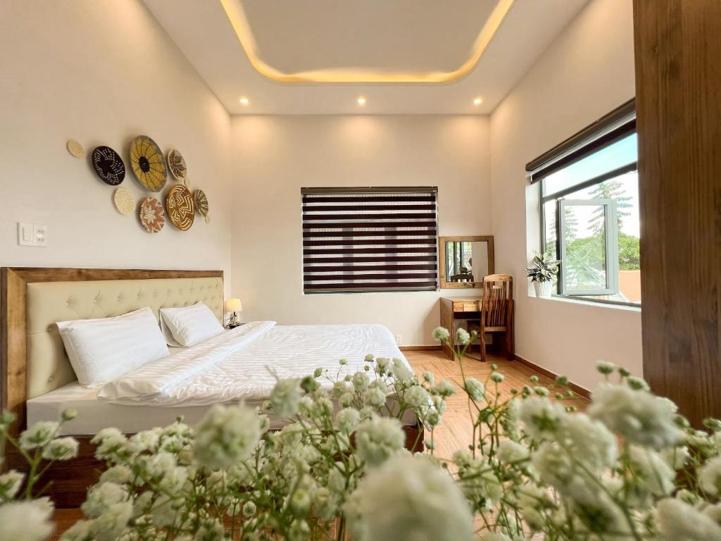 a bedroom with a bed and a window and flowers at Villa Trung Nghĩa 36 in Ấp Ða Lợi