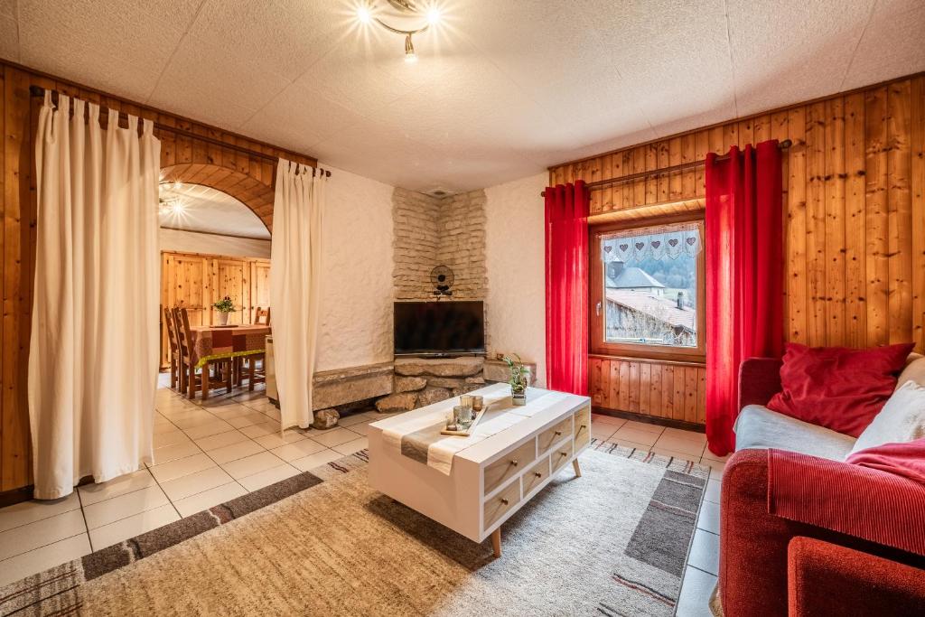 uma sala de estar com um sofá vermelho e uma mesa em Chez les Charles em Bernex