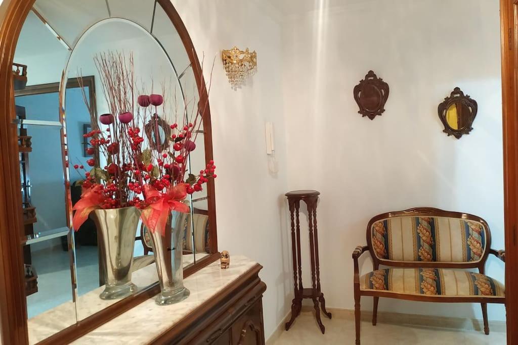a mirror on top of a dresser with a vase of flowers at Piso espacioso en el centro con plaza de garage in Ribeira