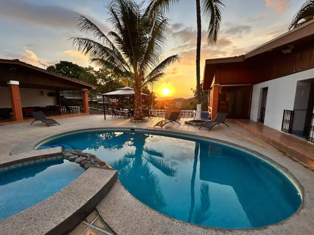 阿拉胡埃拉的住宿－Uruka Lodge，一座游泳池,位于一座享有日落美景的房屋前