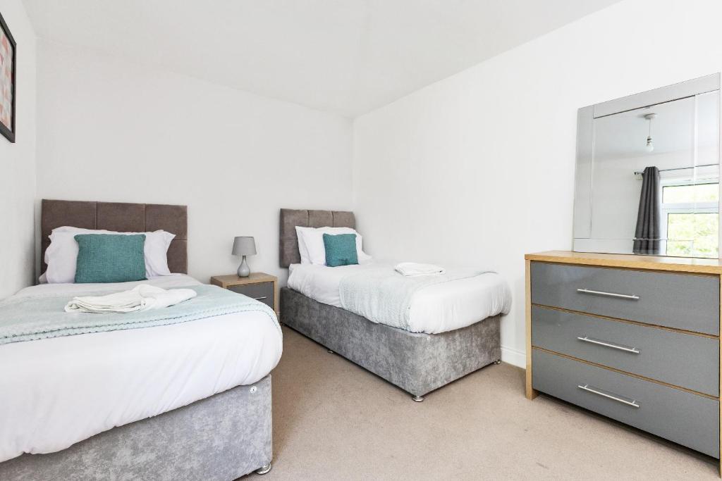 a bedroom with two beds and a dresser with a mirror at OPP B'ham - Freshly refurbished walls and carpets! BIG SAVINGS booking 7 days or more! in Marston Green