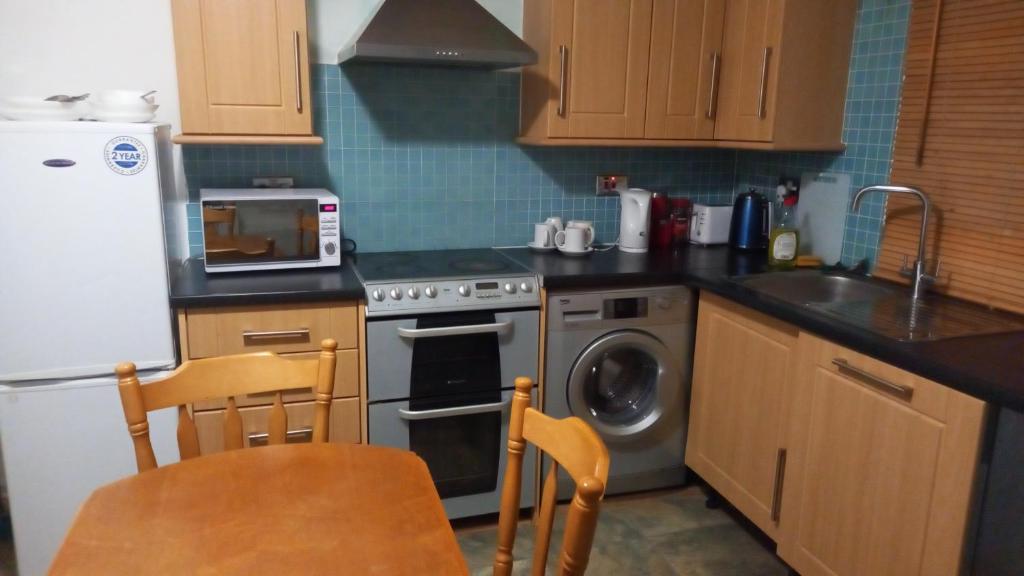 a kitchen with a stove and a sink and a dishwasher at Double En-suite Rooms in Nevendon