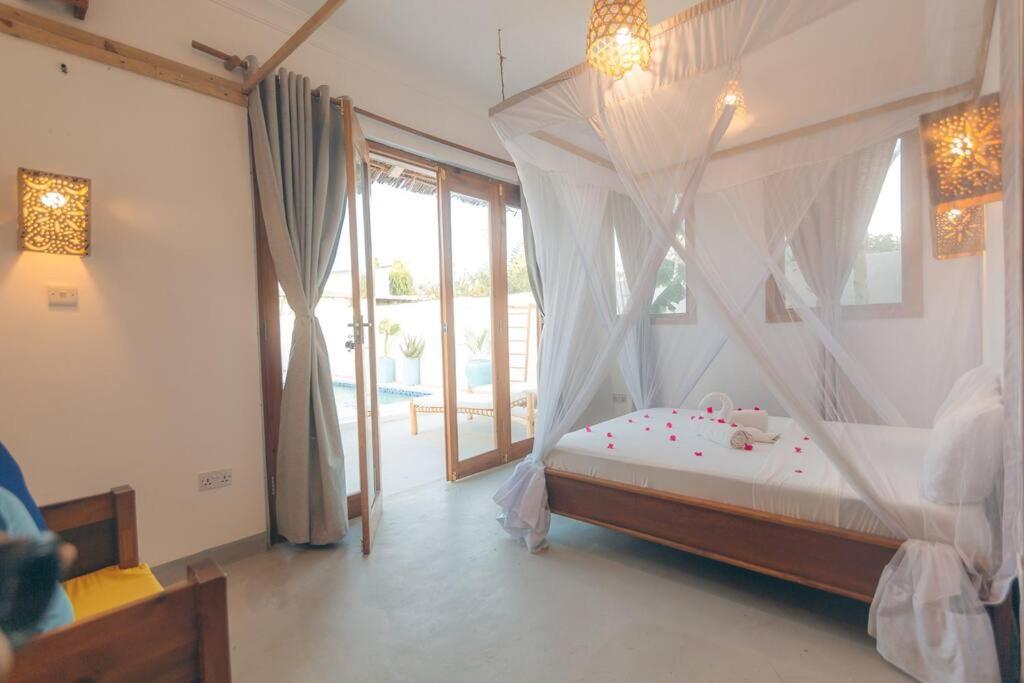 a bedroom with a bed with a mosquito net at Bukoba Villas - Olive - Private Pool, AC & Wi-Fi in Nungwi