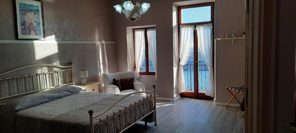 Schlafzimmer mit einem Bett, einem Stuhl und Fenstern in der Unterkunft Casale Massina APPARTAMENTO GIADA in Salò