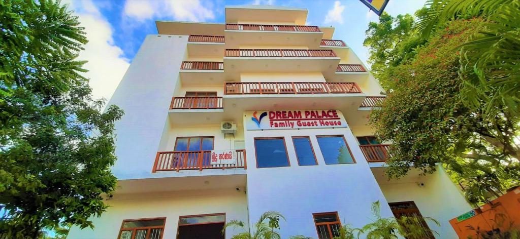 a tall white building with a sign on it at Dream Palace Family Guest House Mirissa in Mirissa