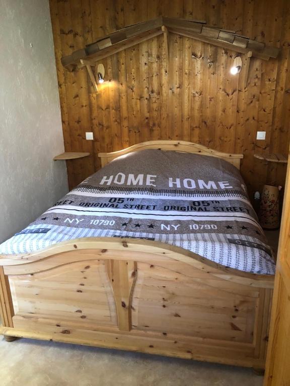 Ce lit en bois se trouve dans une chambre dotée d'un mur en bois. dans l'établissement Princesse jonquille, à Demi-Quartier