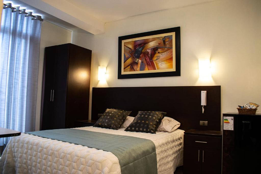 1 dormitorio con 1 cama y una pintura en la pared en Hotel Hatunkay Chaclacayo, en Lima