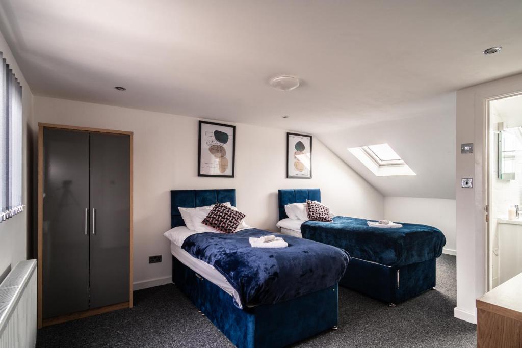a bedroom with two beds and two blue ottomans at Refined Comforts for Two Room 5 in Manchester