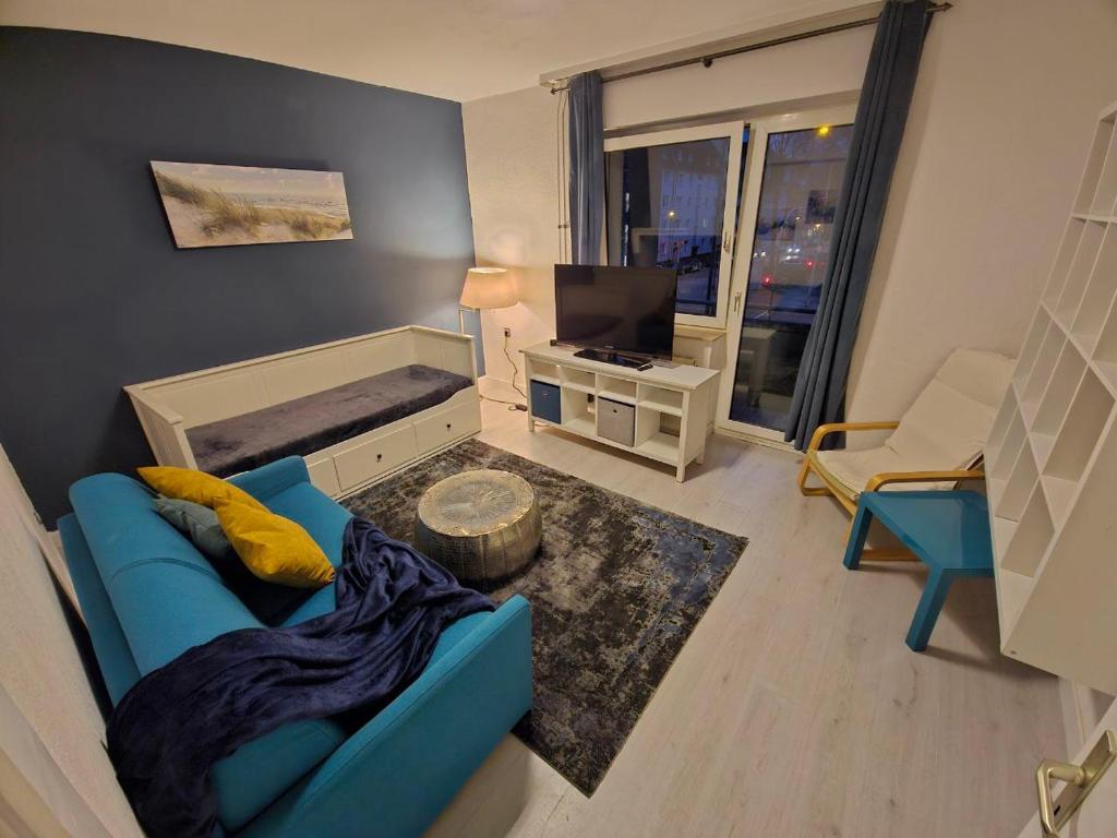 a living room with a blue couch and a television at Flora furnished fair apartments in Essen