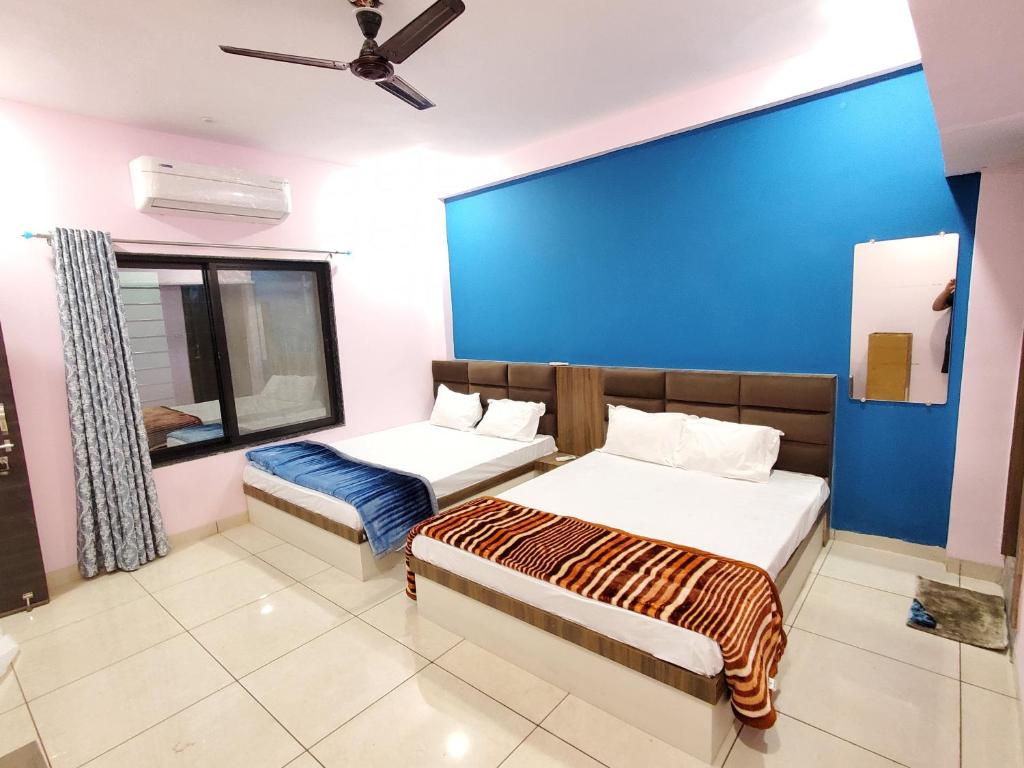 ein Schlafzimmer mit 2 Betten und einer blauen Wand in der Unterkunft Shridham Homestay in Ujjain