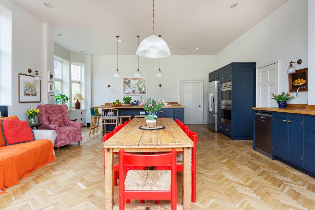 a kitchen with blue cabinets and a table with red chairs at Veeve - Richmond Accents in London
