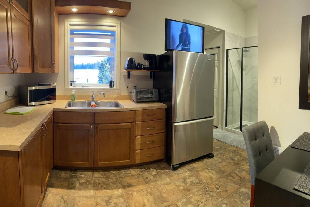 a kitchen with a stainless steel refrigerator and a sink at Studio entièrement privé aux quatre vents in Lac-Mégantic