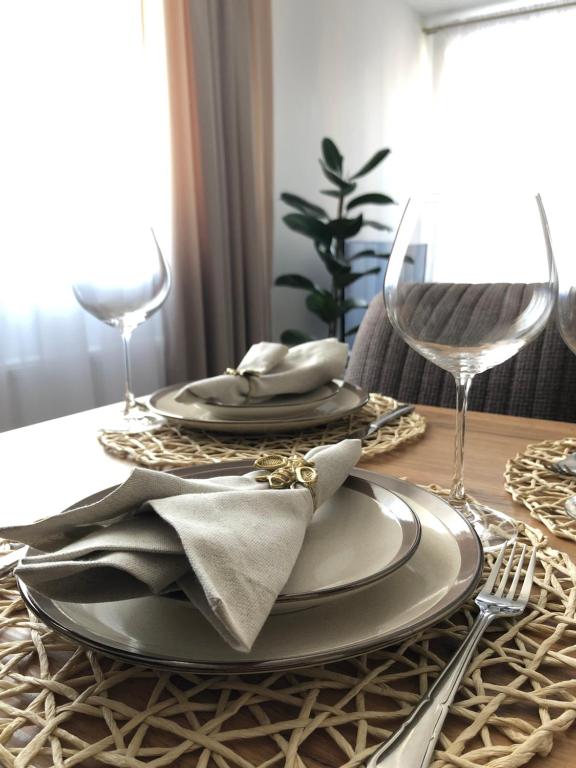 una mesa de comedor con platos y copas de vino en Saulės Tako apartamentai, en Druskininkai