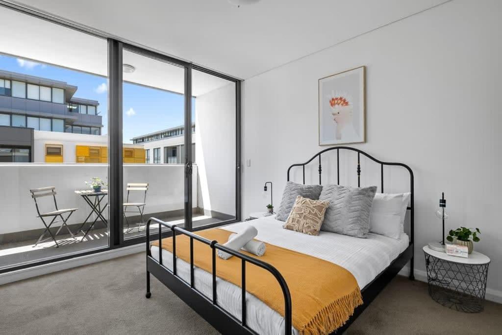 ein Schlafzimmer mit einem Bett und einem großen Fenster in der Unterkunft NEW 3BR Apt in Kingsgrove Sleeps 7 in Sydney