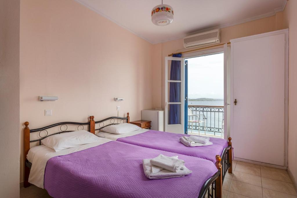 Un dormitorio con una cama con sábanas moradas y una ventana en Stelios Hotel, en Spetses