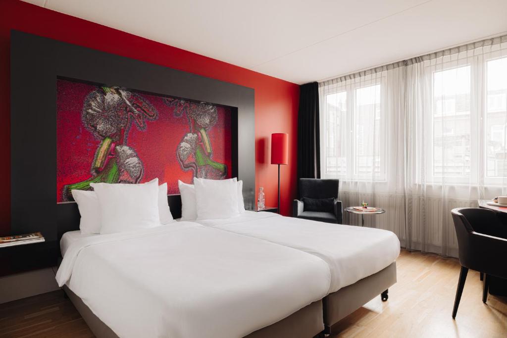 a bedroom with a large bed and a red wall at Designhotel Maastricht in Maastricht