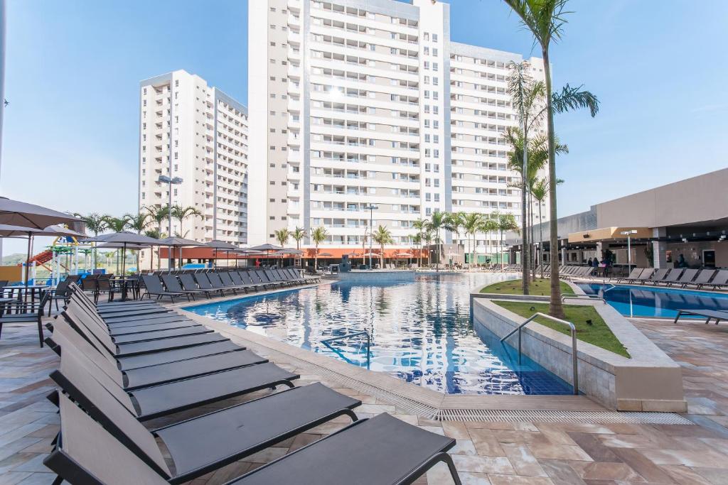 a swimming pool with lounge chairs and a large building at Ideal para famílias, hospede-se no Solar das Águas. in Olímpia