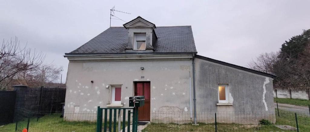 una pequeña casa blanca con una puerta roja en Maison de campagne en cours de rénovation dans un village en bord de Loire, en Saint-Mathurin