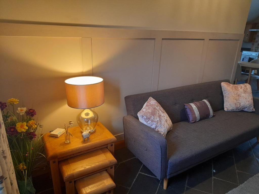 een woonkamer met een bank en een tafel met een lamp bij Quarry Loft in Magherafelt