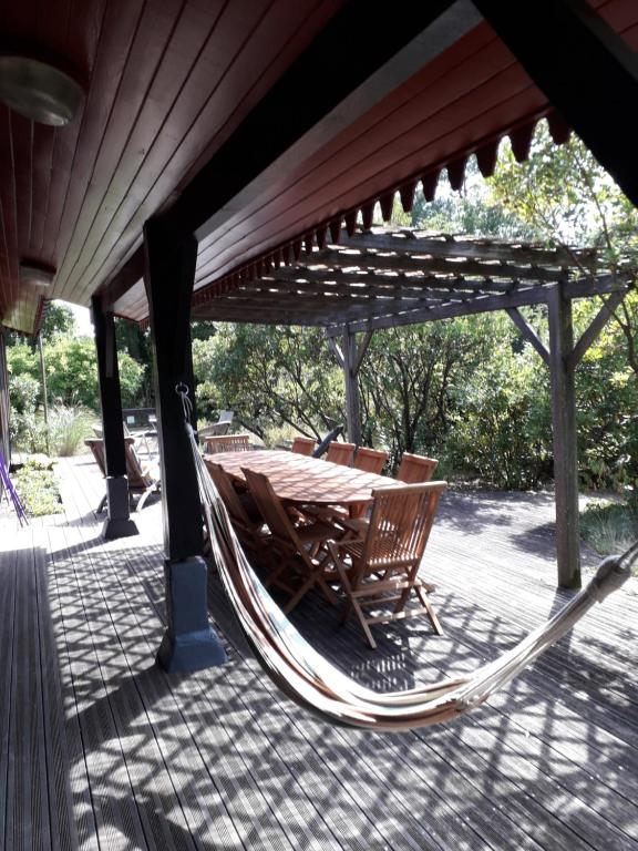 a hammock and a table and chairs under a roof at villa les Arbousiers in Vieux-Boucau-les-Bains