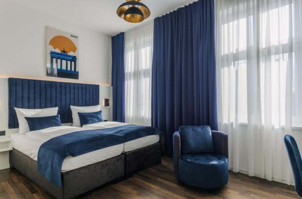1 dormitorio con cortinas azules, 1 cama y 1 silla en Homaris East Side Hotel - Mobile Key Access, en Berlín