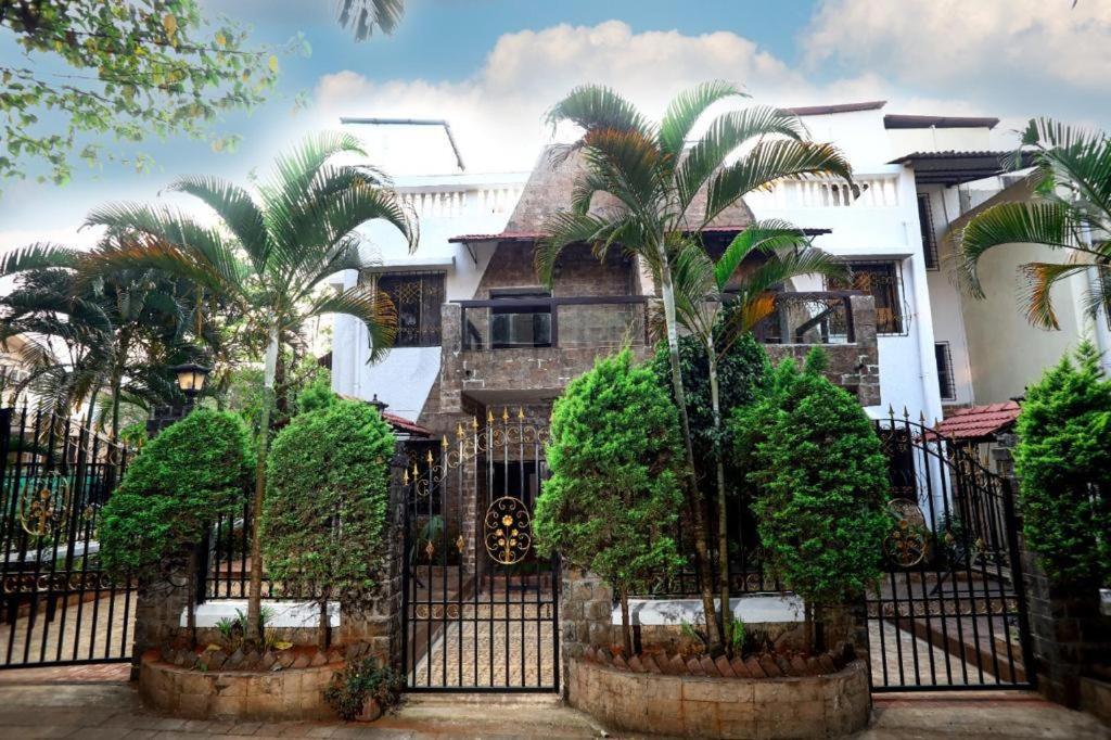 a house with palm trees in front of a fence at CORAL VILLA in Lonavala