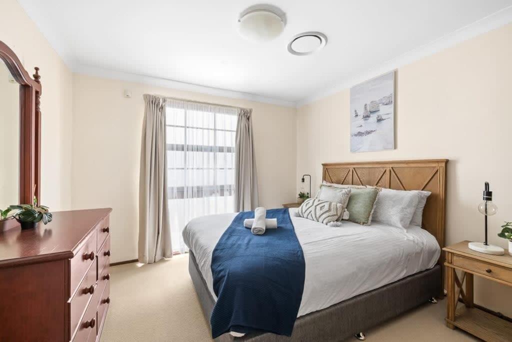 a bedroom with a large bed and a window at Beautiful Home In Milperra Sleeps 8 in Sydney