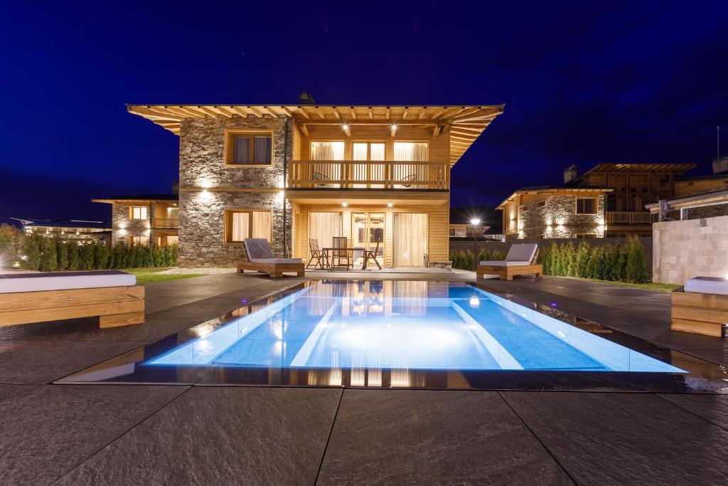 una piscina frente a una casa por la noche en Solis Thermal Villas- HOT pool, en Banya