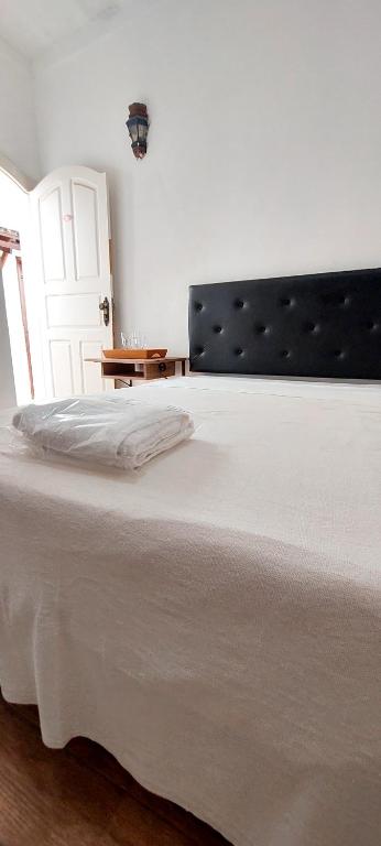 a bedroom with a large white bed with a black headboard at Suítes da Praça Tiradentes in Tiradentes