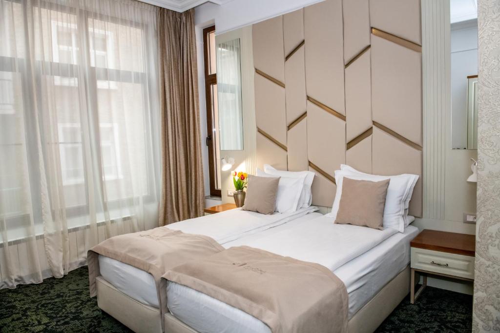 a bedroom with a large white bed with a wooden headboard at Agora' Boutique Self-Check In in Sofia