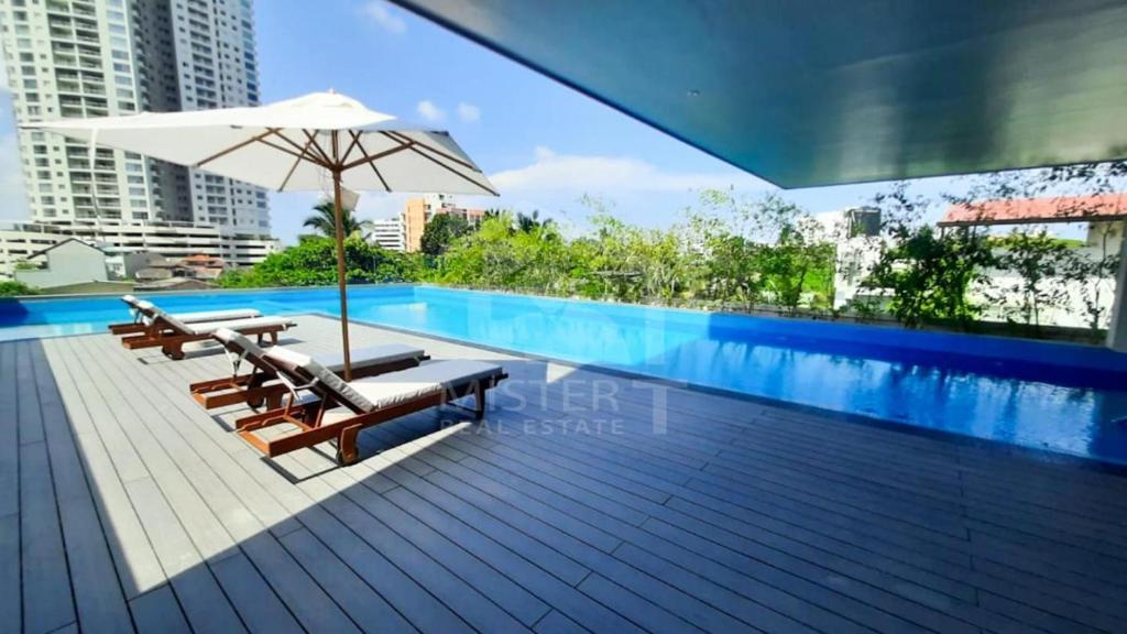a swimming pool with chairs and an umbrella at 3 Bedroom Apartment - Iconic Residences Colombo in Sri Jayewardenepura Kotte