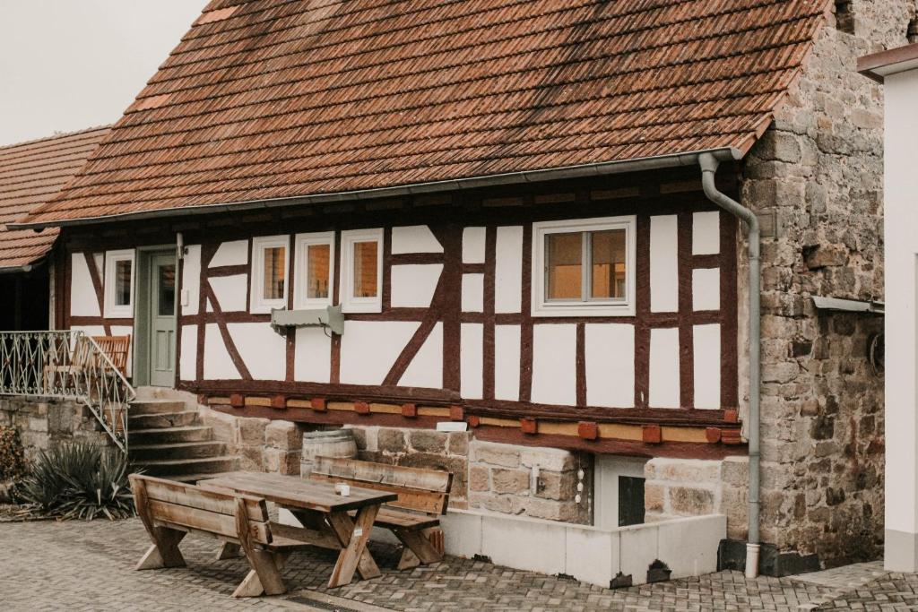 um edifício com uma mesa e um banco à sua frente em Ferienwohnung Ziegler em Ebersburg