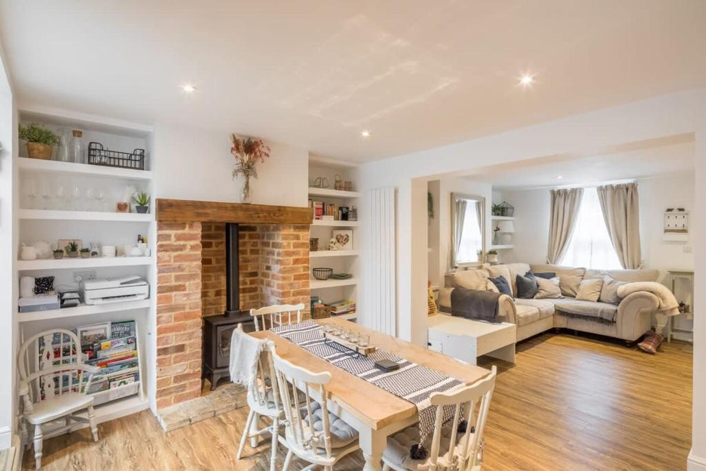 a living room with a table and a fireplace at Charming Cambridge Cottage With Lovely Garden 
