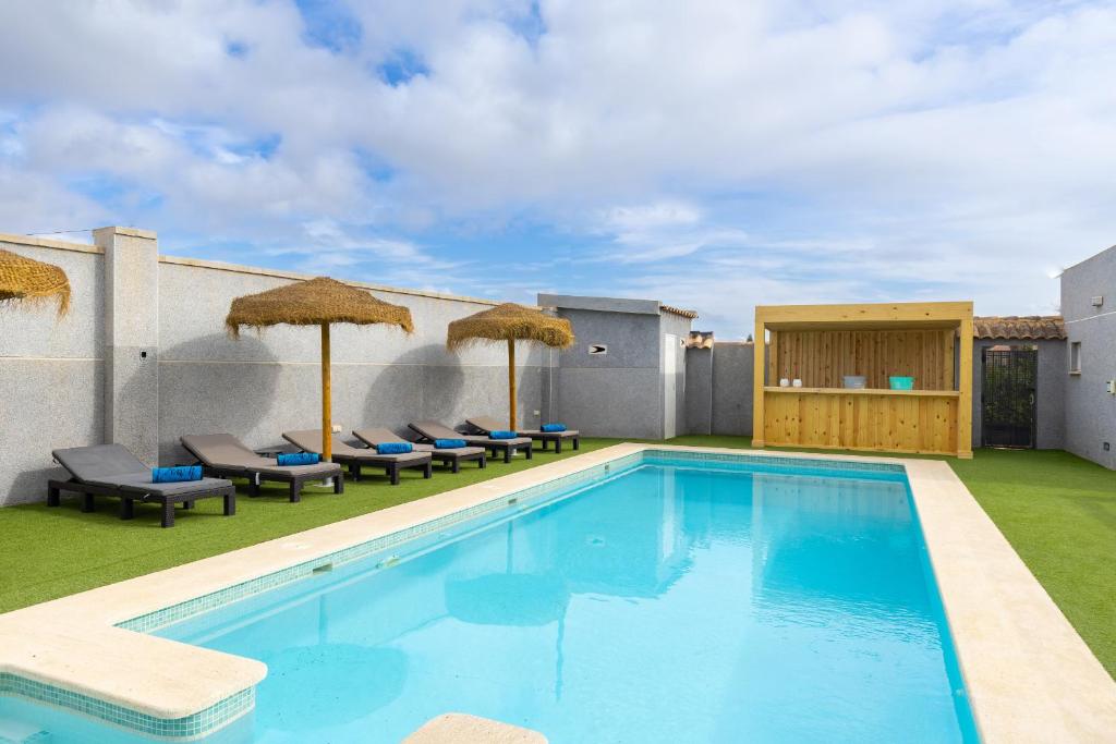 een zwembad met stoelen en parasols naast een gebouw bij WaterWheel Villa by Fidalsa in Almoradí