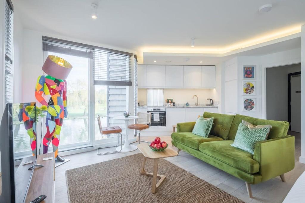 ein Wohnzimmer mit einem grünen Sofa und einer Küche in der Unterkunft Luxurious Central Apartment with Balcony in Cambridge