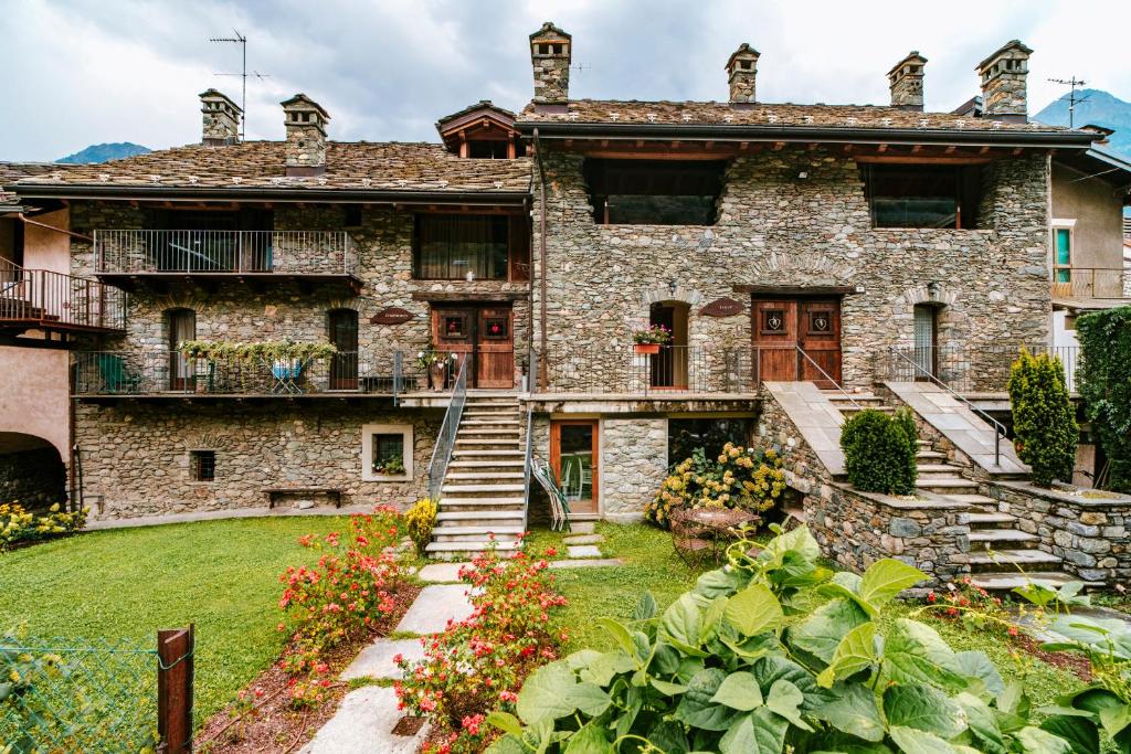 an old stone house with a garden in front of it at Maison Rosset agriturismo, camere, APPARTAMENTI e spa in Valle d'Aosta in Nus