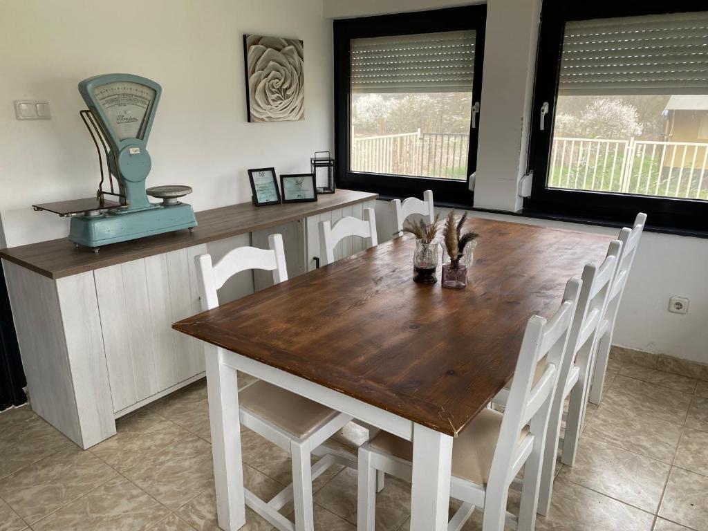 a dining room with a wooden table and white chairs at BG Apartments in Somogyhatvan