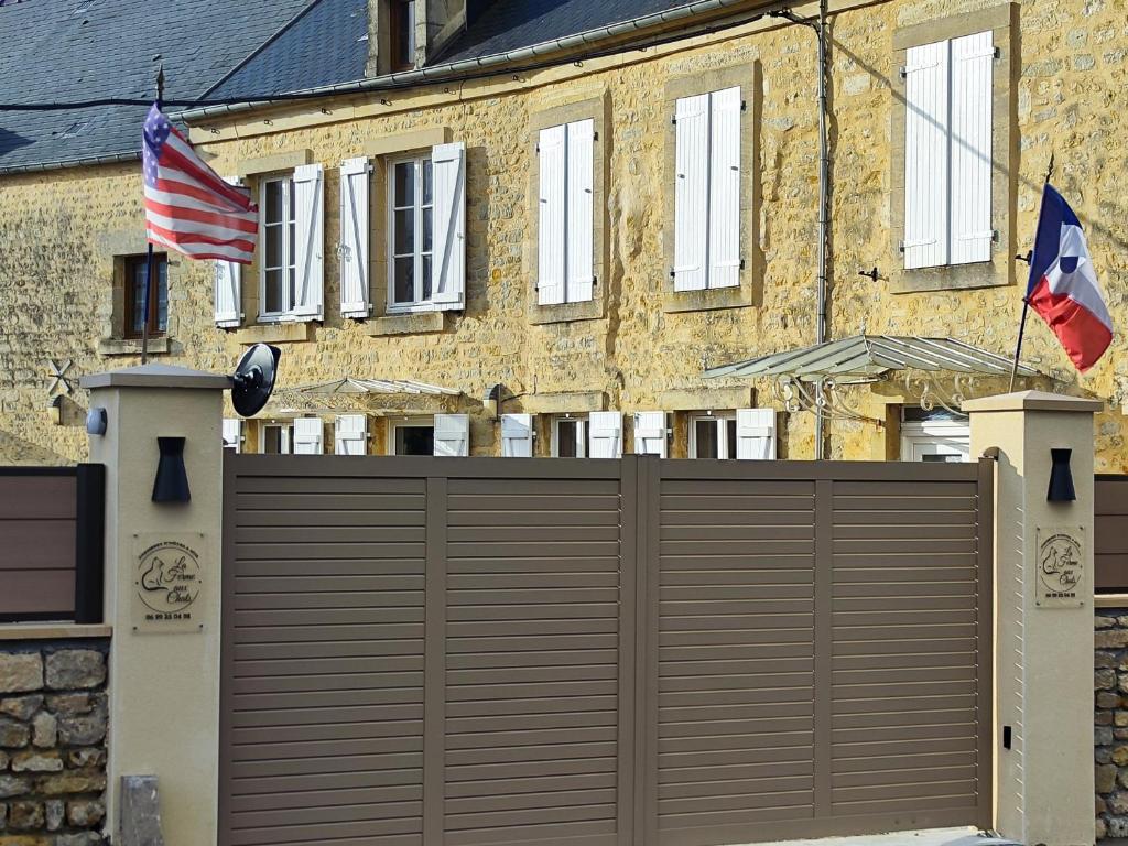 two american flags are flying next to a garage at La ferme aux chats in Formigny