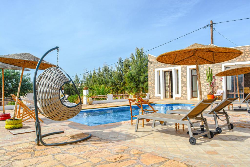 Villa Mama comfort et hospitalité في الصويرة: مسبح مع كرسيين ومظلتين بجانب مسبح
