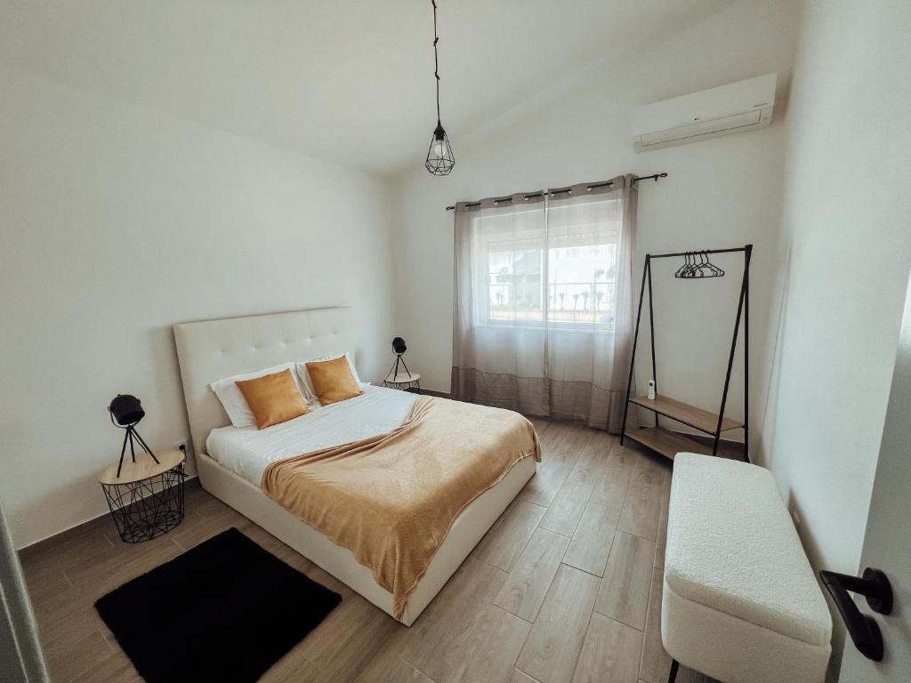 um quarto branco com uma cama e uma janela em Casa Dom Simões em Aljezur