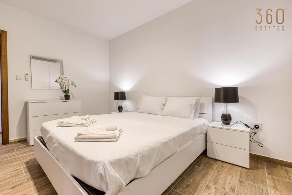 a white bedroom with a large bed with towels on it at Bright &amp; cosy 3BR home with private balcony &amp; WIFI by 360 Estates in Dingli
