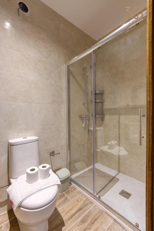 a bathroom with a toilet and a glass shower at Bright &amp; cosy 3BR home with private balcony &amp; WIFI by 360 Estates in Dingli