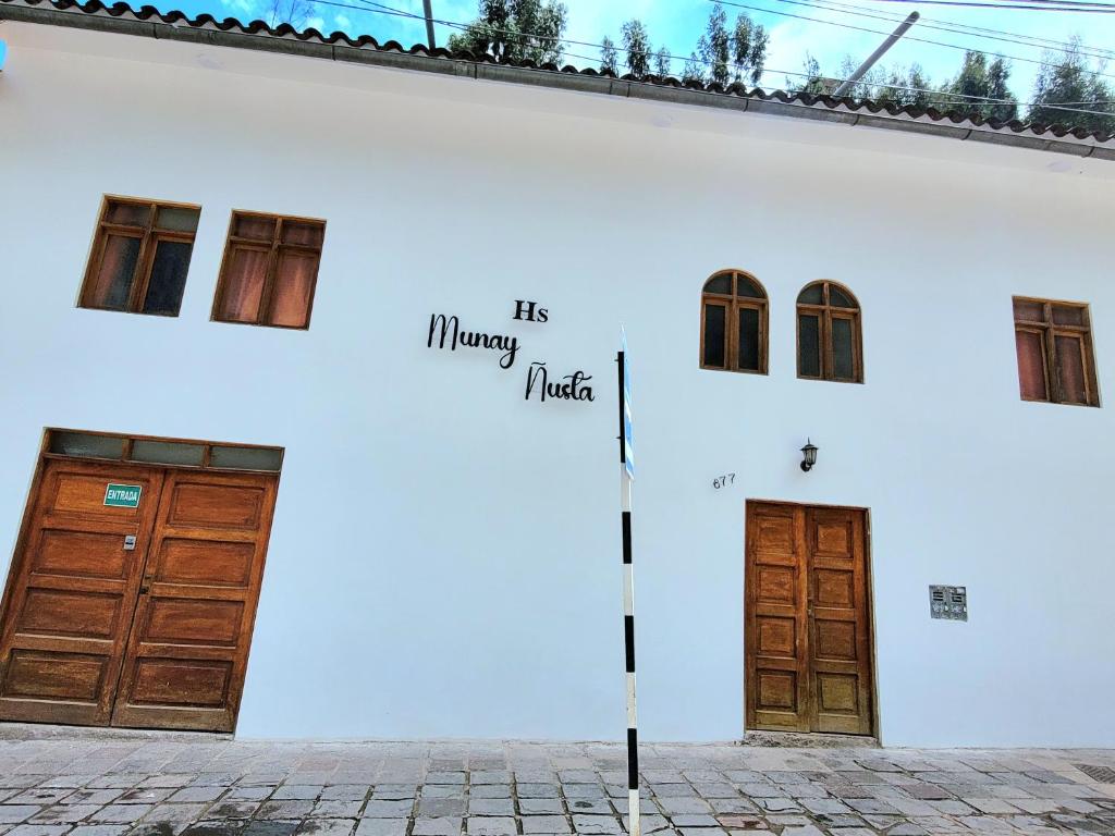 un edificio blanco con dos puertas y las palabras su música feliz en Munay Ñusta, en Cusco