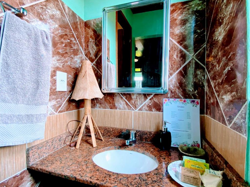 ein Bad mit einem Waschbecken und einem Spiegel in der Unterkunft Hospedaria do Tom in Lençóis