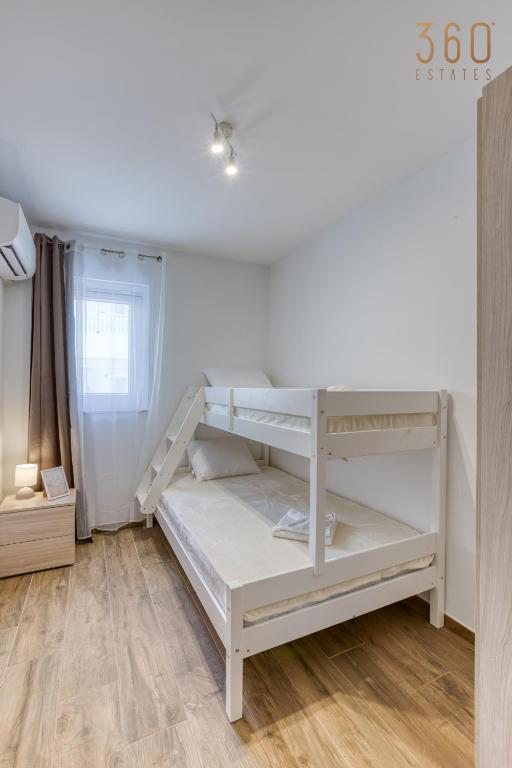 a white bunk bed in a room with a wooden floor at Bright &amp; cosy 3BR home with private balcony &amp; WIFI by 360 Estates in Dingli