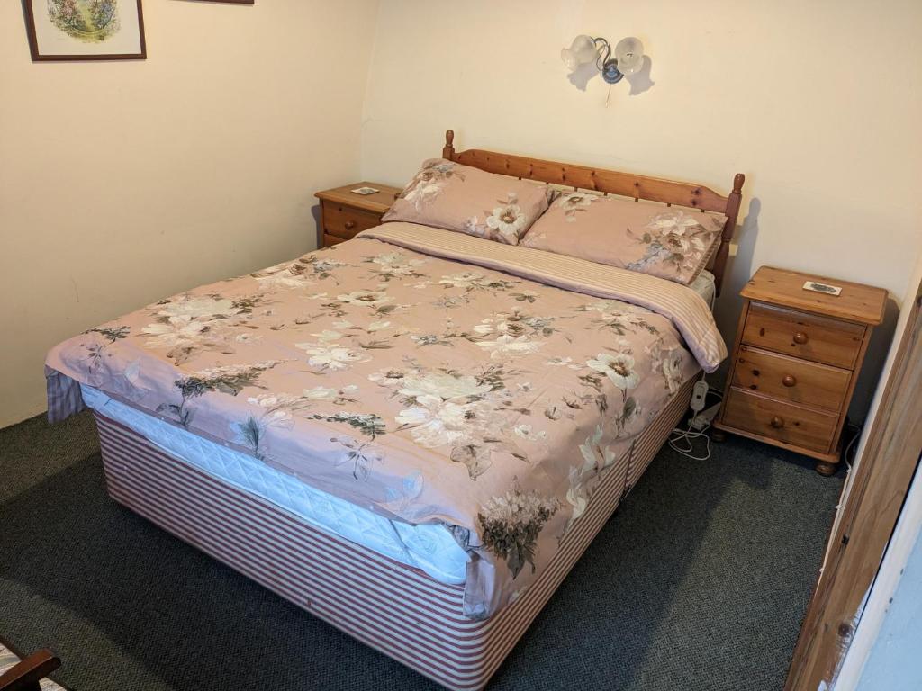 a bedroom with a bed and a night stand at Rosecare Barn in Bude
