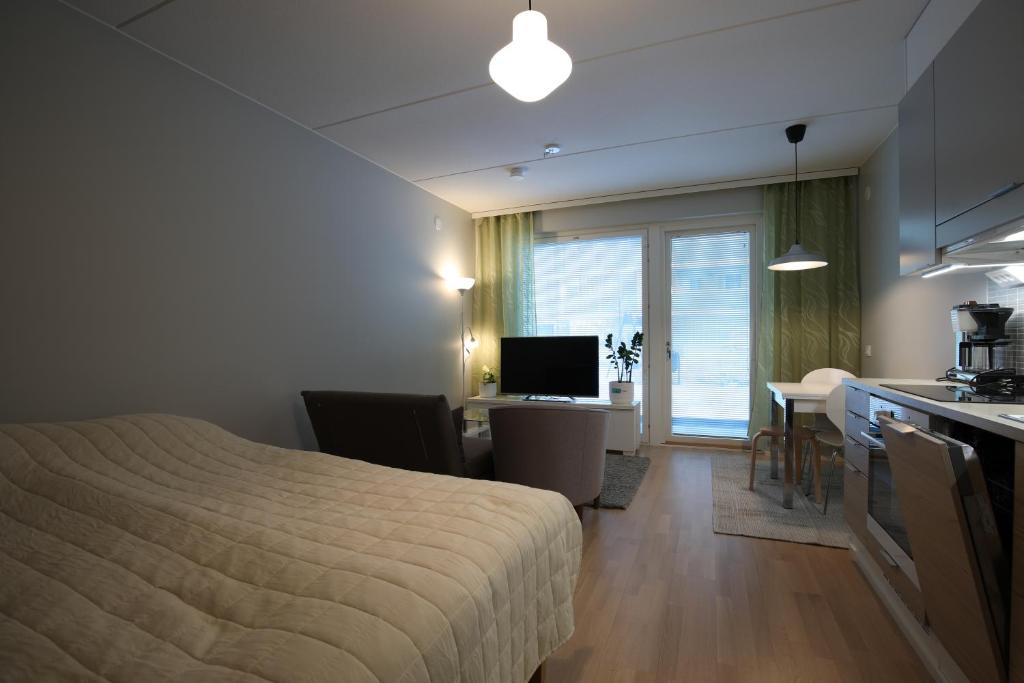 a bedroom with a bed and a kitchen with a desk at Hieno yksiö Tapiolan urheilupuistossa. in Espoo